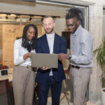 Professionals discussing reseller sales models on a laptop in a modern office.